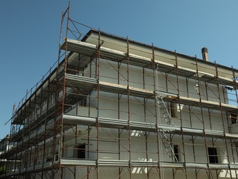 Photo of Unfinished building with scaffolding outdoors on sunny day