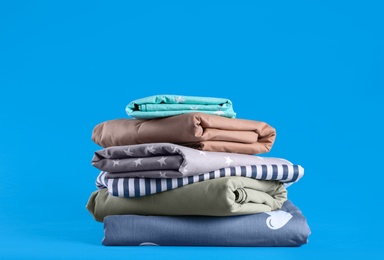 Photo of Stack of clean bed sheets on blue background