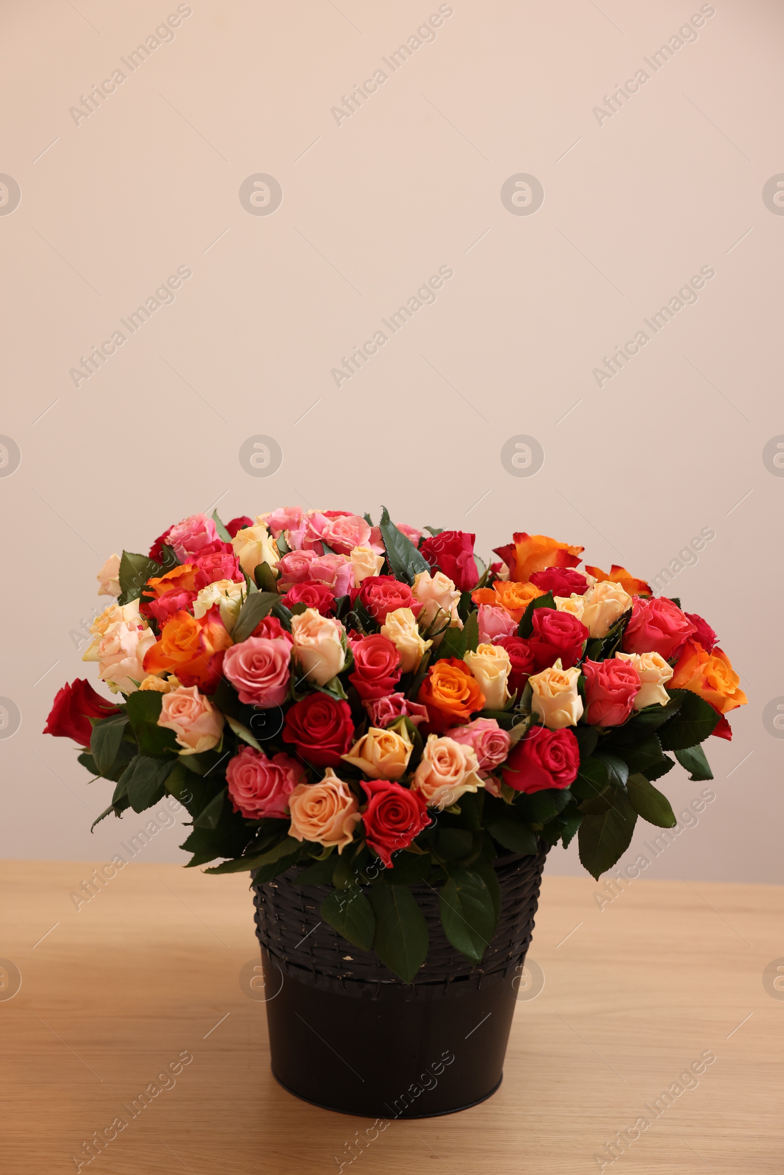 Photo of Bouquet of beautiful roses on wooden table against light background. Space for text