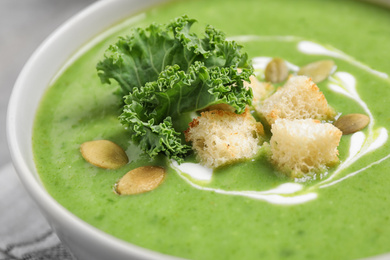 Tasty kale soup with croutons on table, closeup