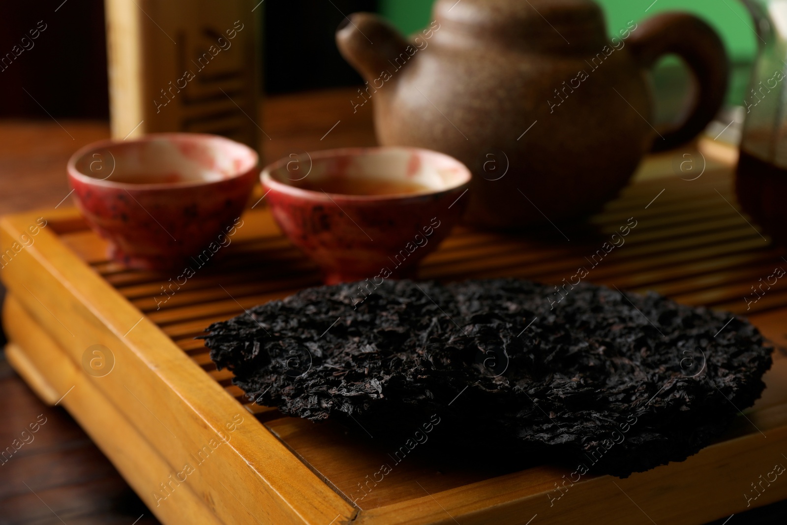 Photo of Broken disc shaped pu-erh tea on wooden tray, closeup