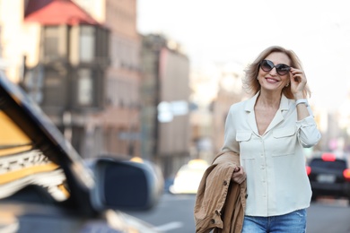 Photo of Beautiful mature woman with sunglasses on city street