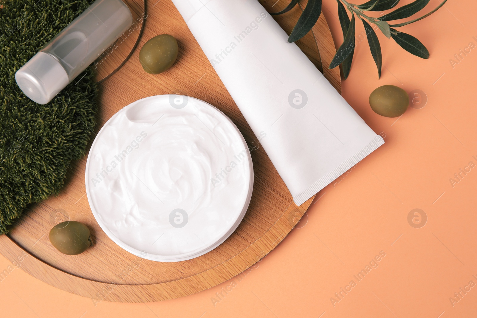 Photo of Flat lay composition with different cosmetic products and olives on pale orange background
