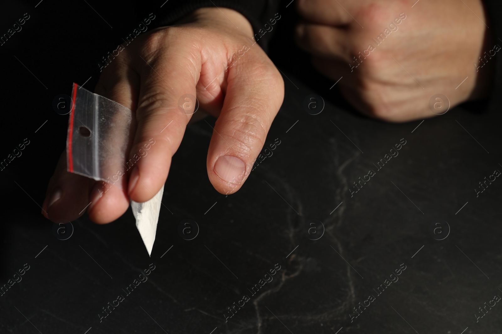 Photo of Drug addiction. Man with plastic bag of cocaine at grey textured table, closeup