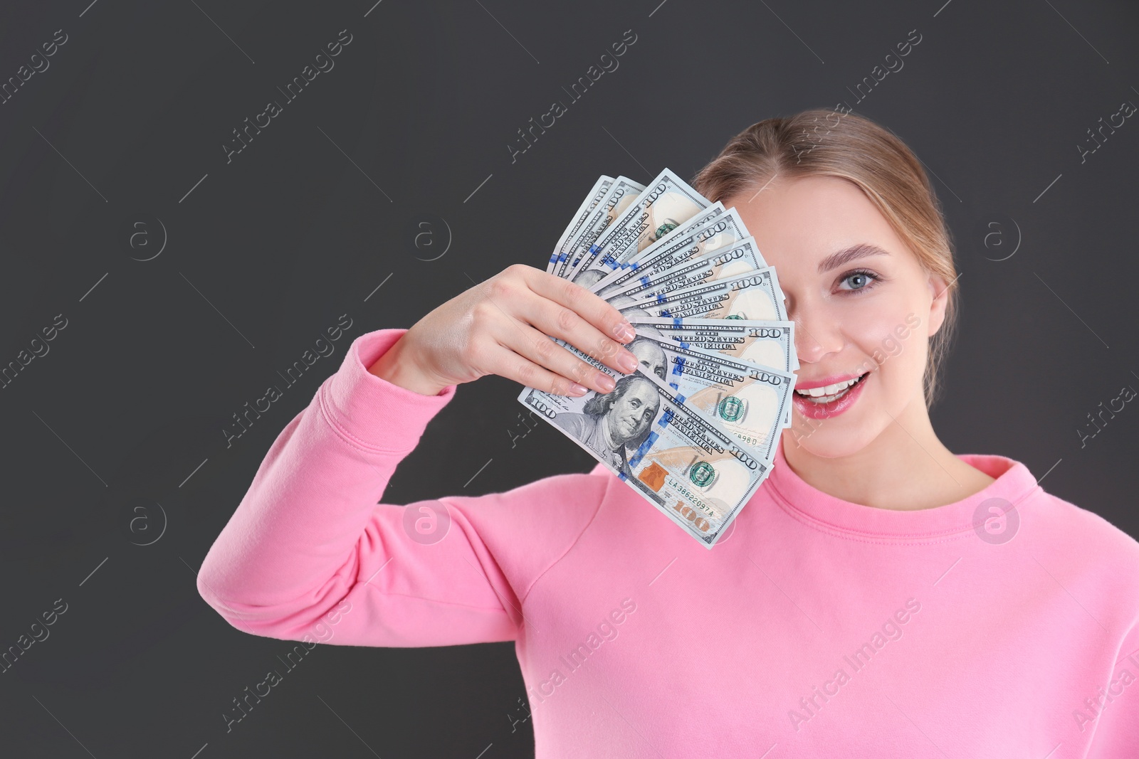 Photo of Portrait of happy young woman with money on grey background