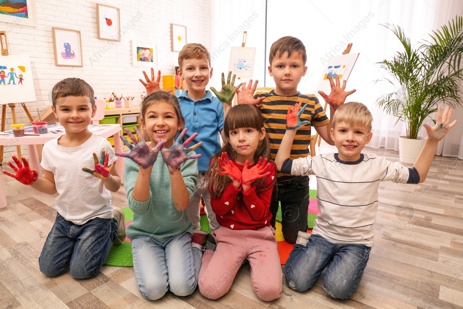 Photo of Cute little children with painted palms in room