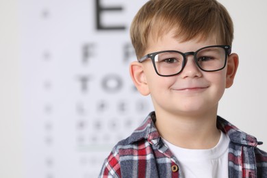 Little boy with glasses against vision test chart