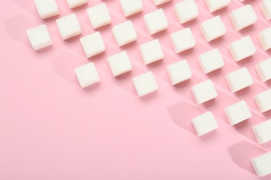 Photo of White sugar cubes on pink background, top view. Space for text