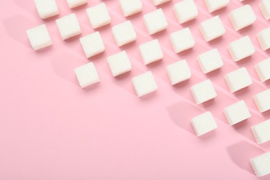 White sugar cubes on pink background, top view. Space for text