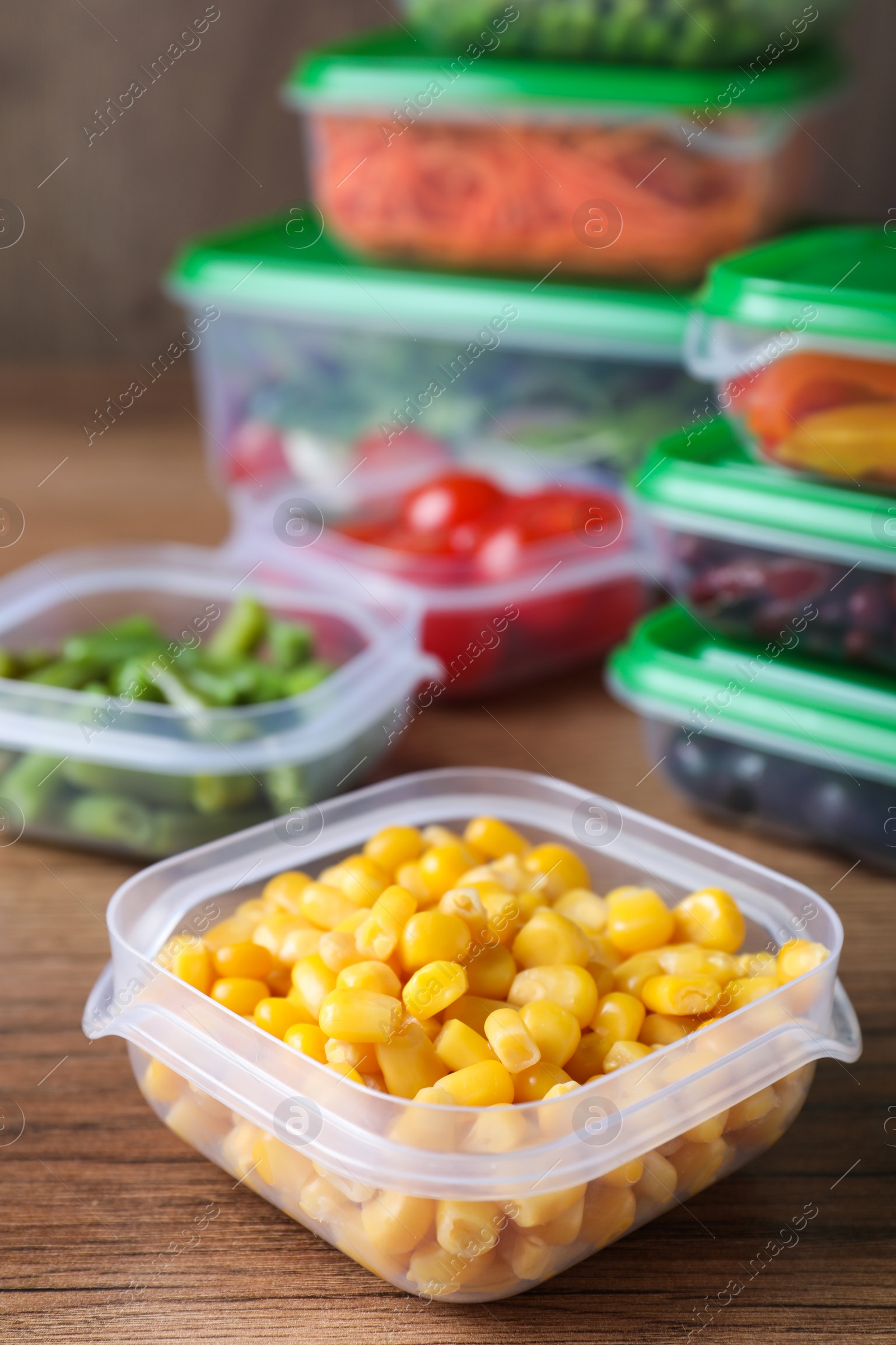 Photo of Fresh corn kernels in plastic container on wooden  table