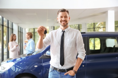 Photo of Salesman with car keys in modern auto dealership