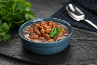 Bowl of canned kidney beans with parsley on grey table, closeup