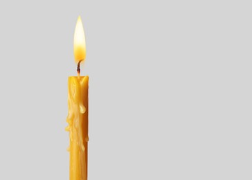 Image of Burning church candle on light background. Space for text