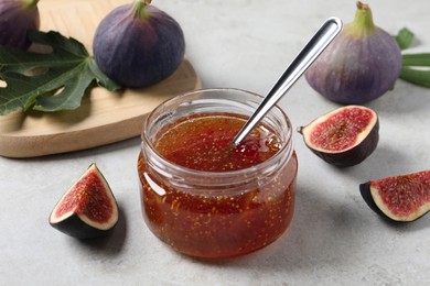 Photo of Jar with tasty fig jam and fresh fruits on white table