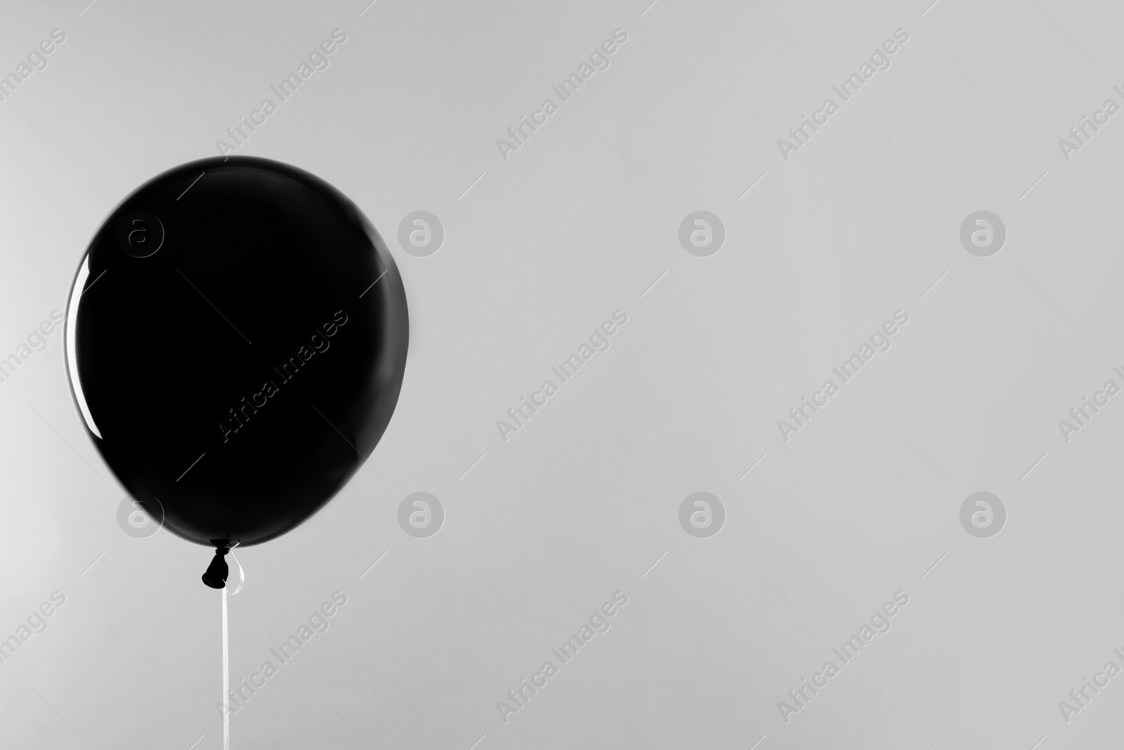 Photo of Black balloon for Halloween party on light grey background, space for text
