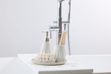 Photo of Different personal care products and accessories on bath tub in bathroom