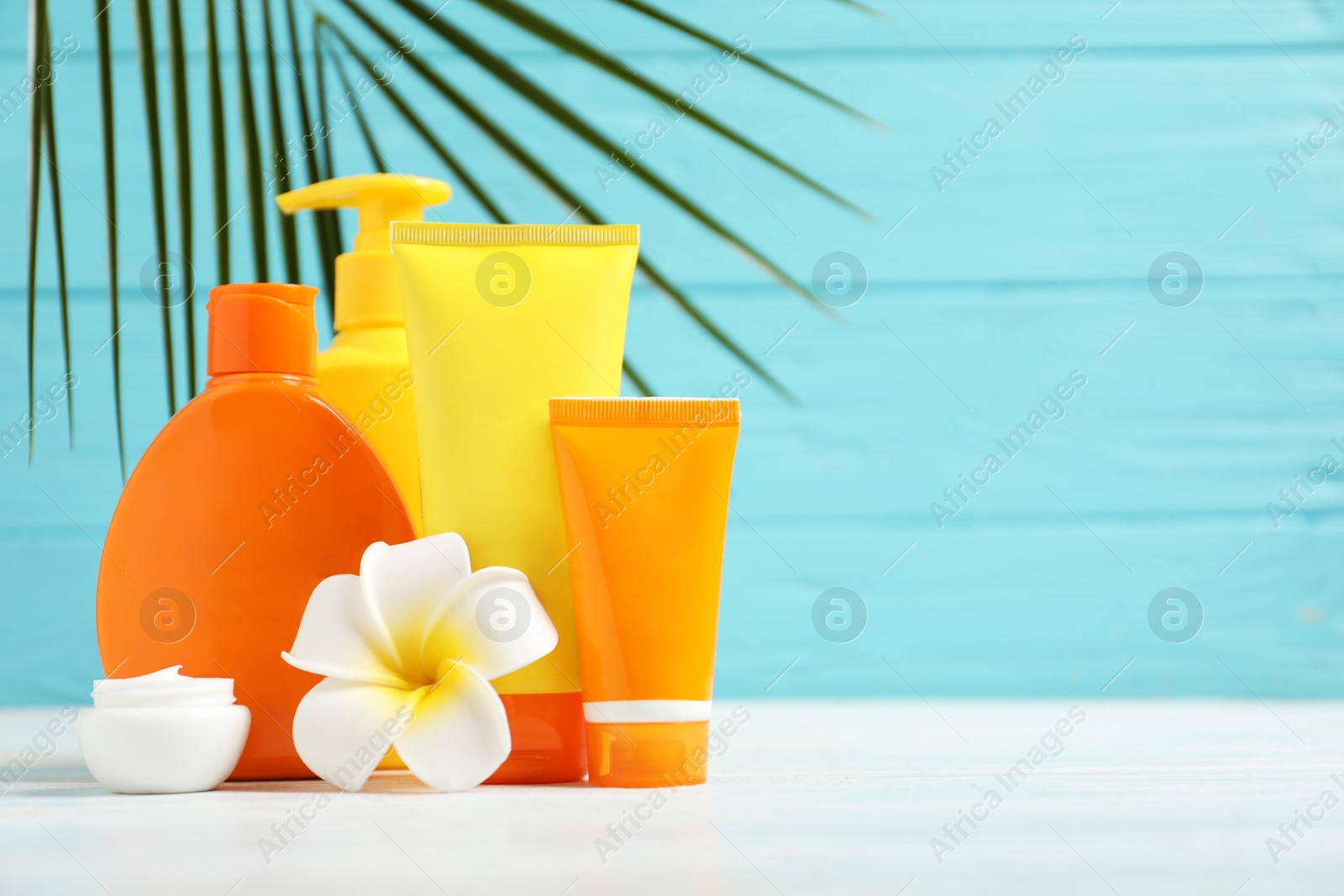 Photo of Composition with sun protection cosmetic products on white table against blue wooden background, space for text