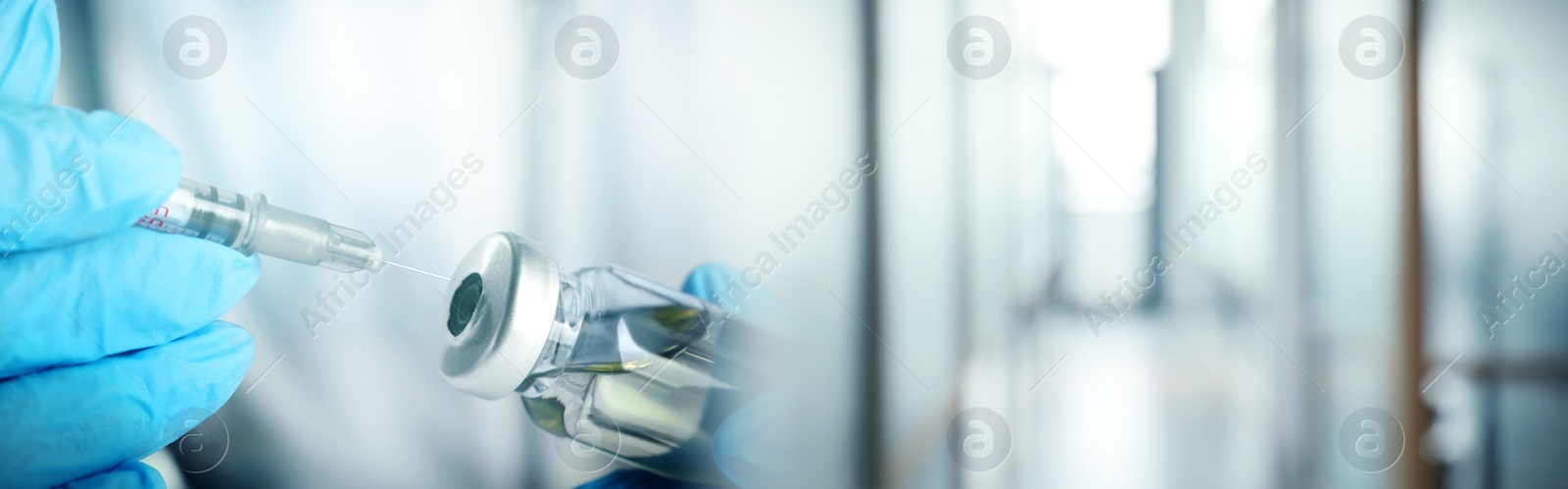 Image of Doctor filling syringe with medication from glass vial on blurred background, closeup. Banner design