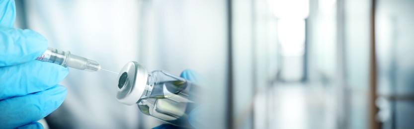 Image of Doctor filling syringe with medication from glass vial on blurred background, closeup. Banner design