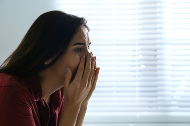 Photo of Abused young woman crying indoors, space for text. Domestic violence concept