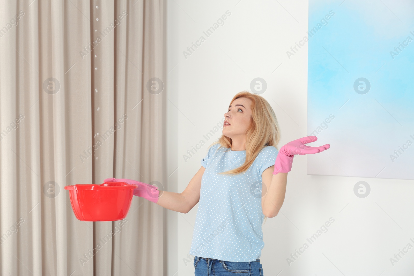 Photo of Woman holding plastic basin under water leakage from ceiling at home