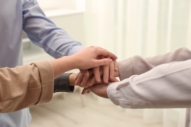 Photo of Group of people holding their hands together on blurred background, closeup