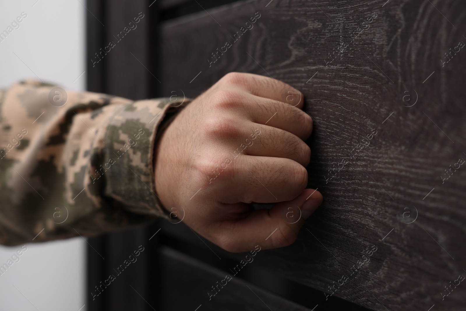 Photo of Military commissariat representative knocking on wooden door, closeup