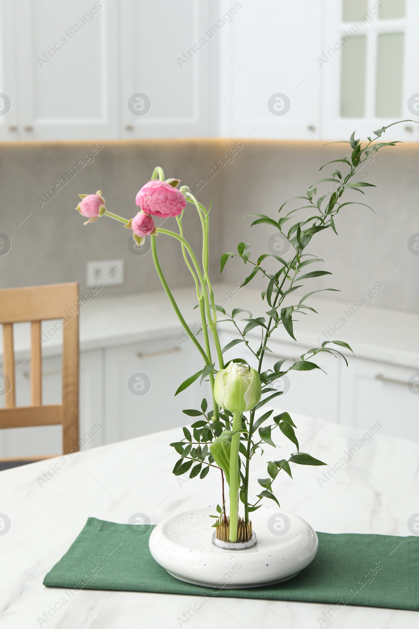 Photo of Ikebana art. Beautiful pink flowers and green branch carrying cozy atmosphere at home