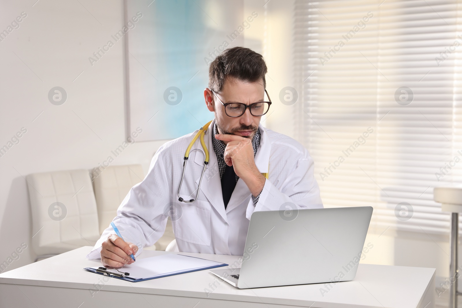 Photo of Pediatrician consulting patient online at table in clinic