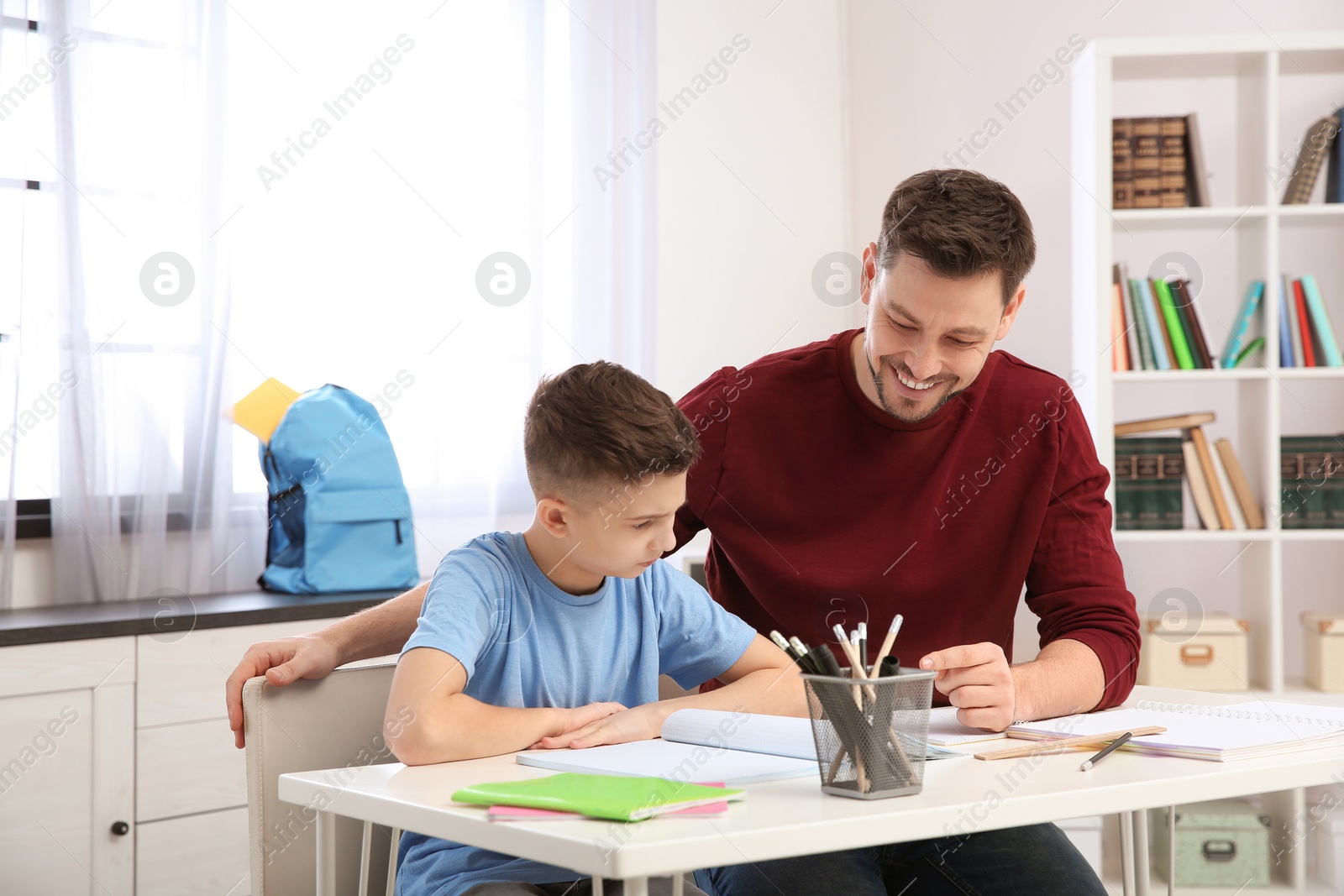 Photo of Dad helping his son with homework in room