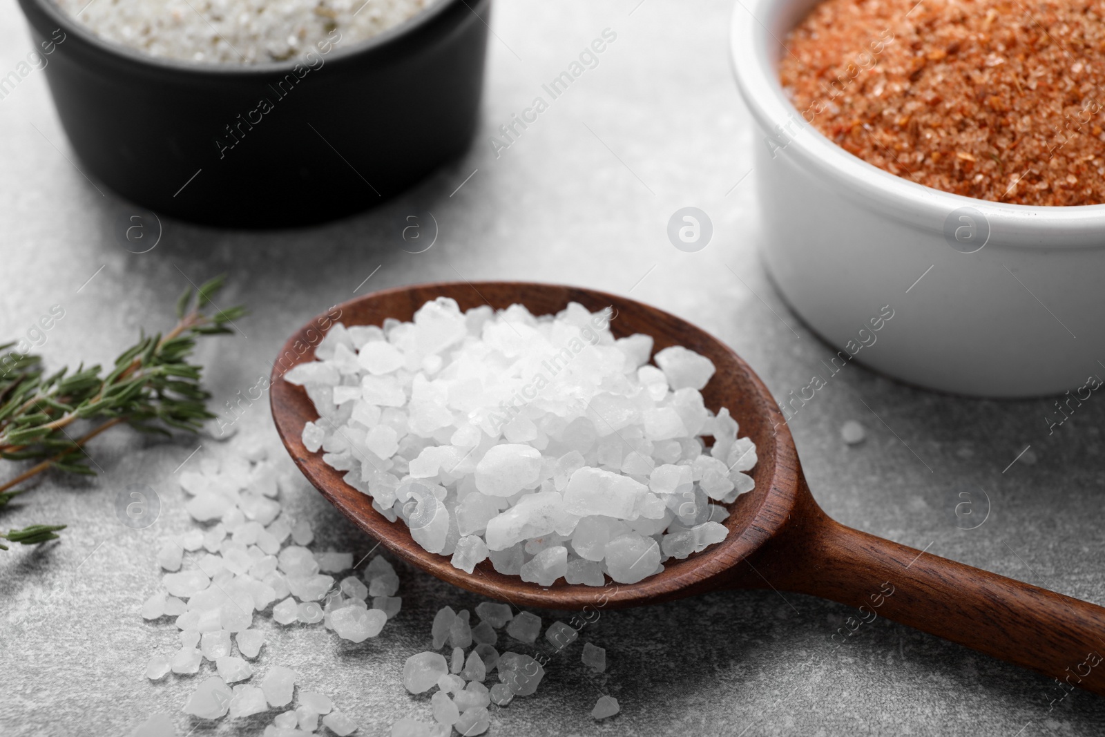 Photo of Different kinds of salt on grey table, closeup