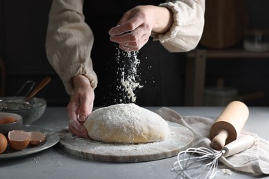 Photo of Making dough. Woman adding flour at grey table, closeup