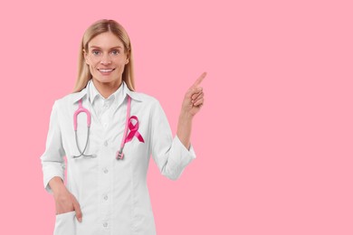 Doctor with pink ribbon and stethoscope on color background, space for text. Breast cancer awareness