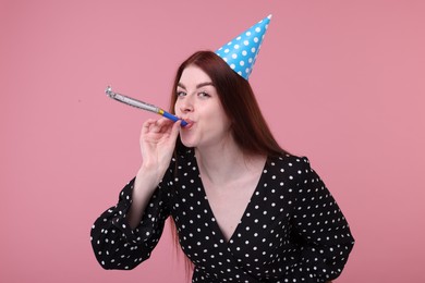 Photo of Young woman in party hat with blower on pink background