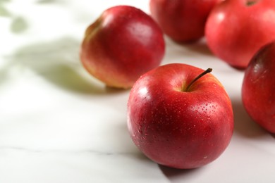 Photo of Fresh red apples with water drops on white table, closeup. Space for text