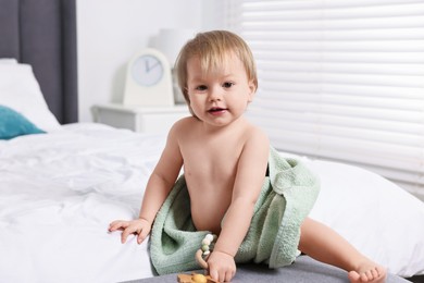 Cute little baby with towel after bathing on bed