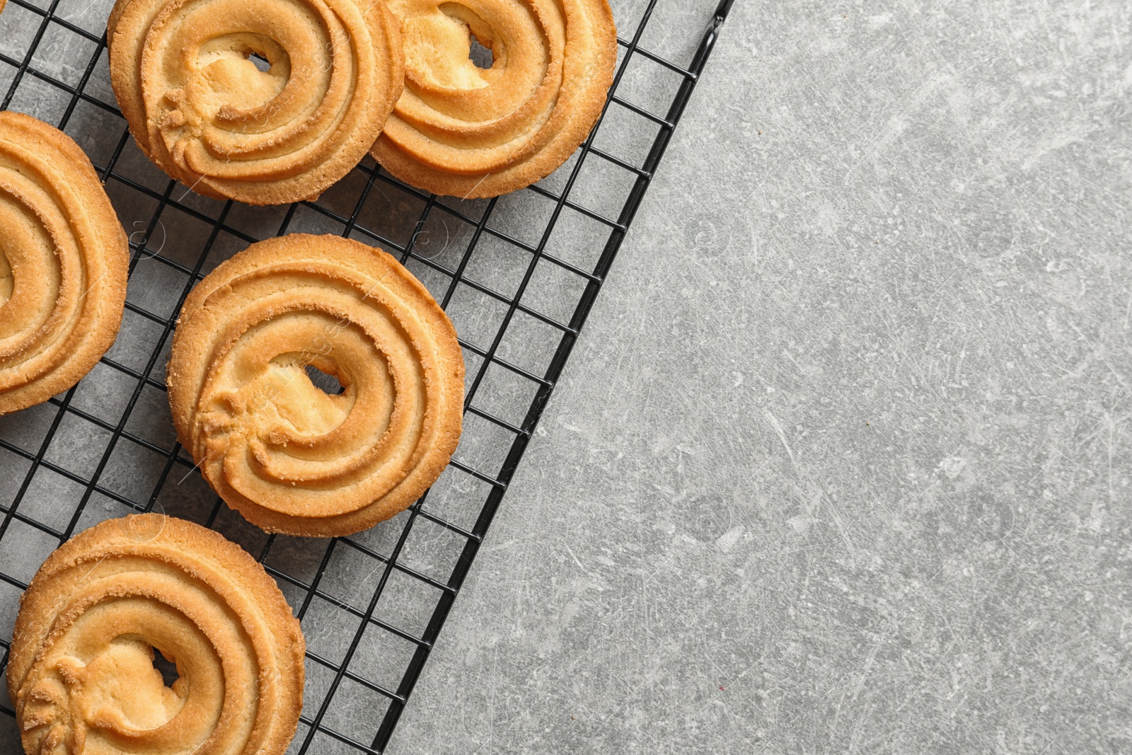 Photo of Baking grid with Danish butter cookies on grey table, top view. Space for text