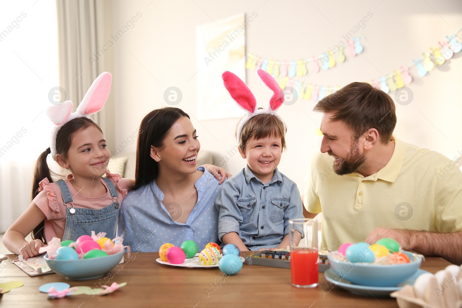 Photo of Happy family painting Easter eggs at table indoors