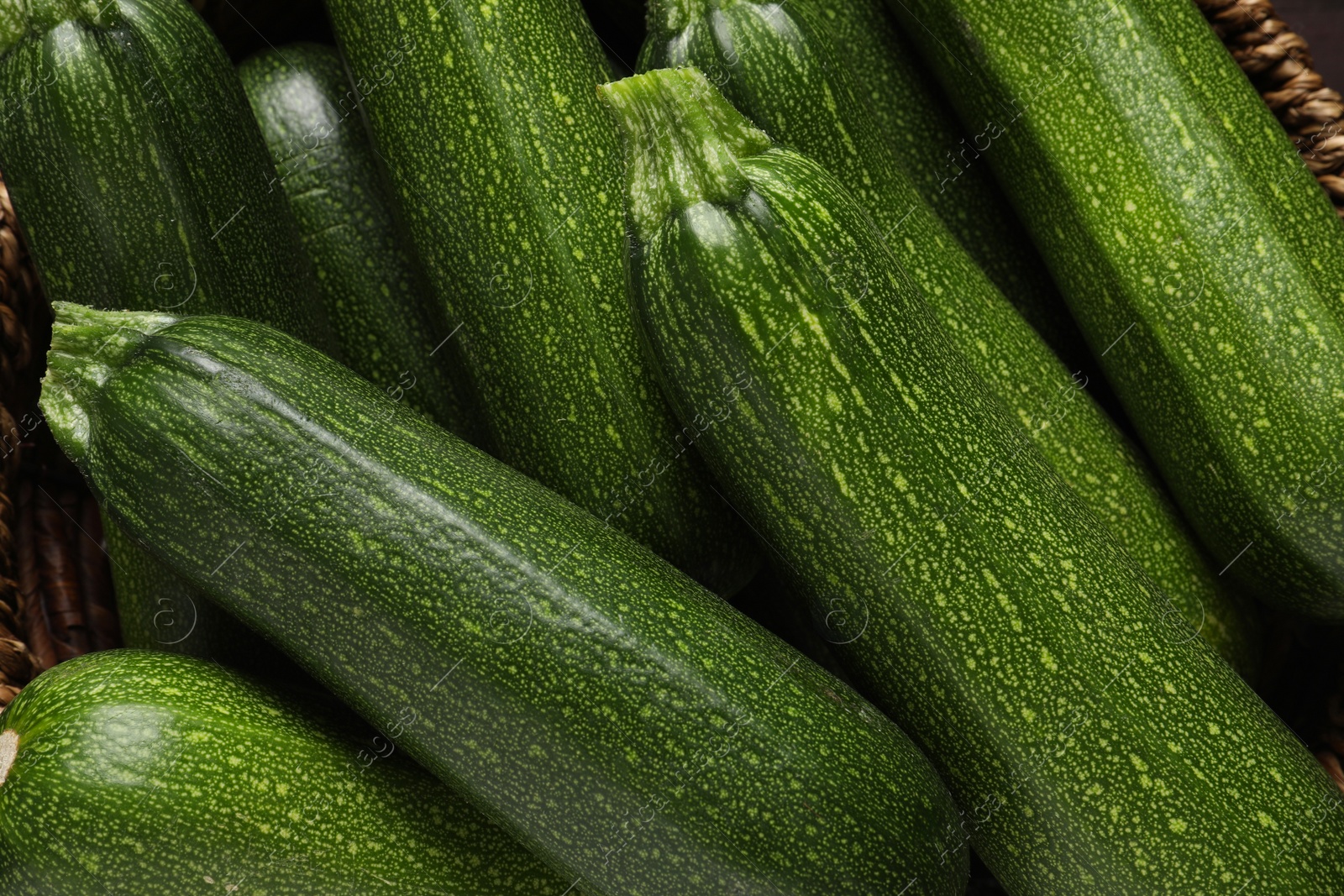 Photo of Raw ripe zucchinis in wicker bowl, closeup