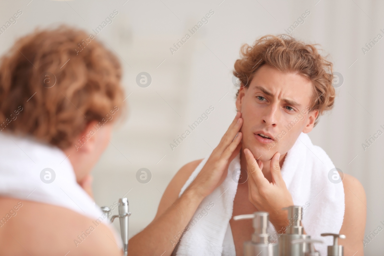 Photo of Young man looking in mirror after shaving at home