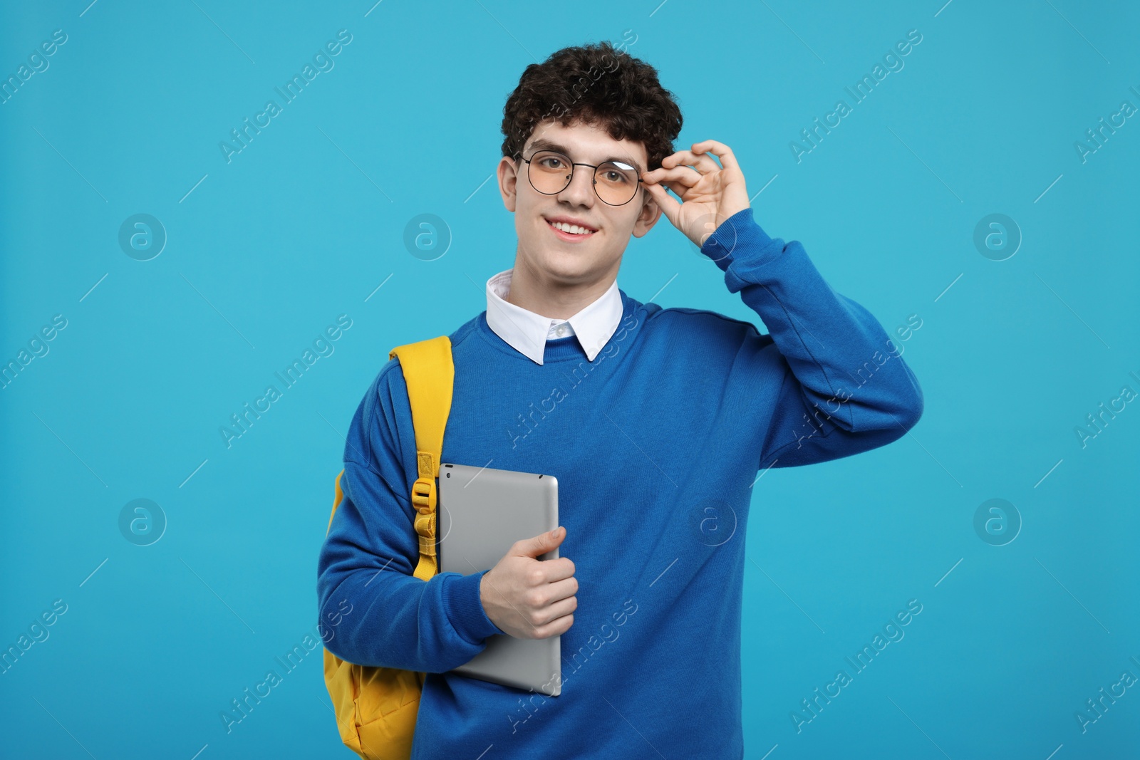 Photo of Portrait of student with backpack and tablet on light blue background