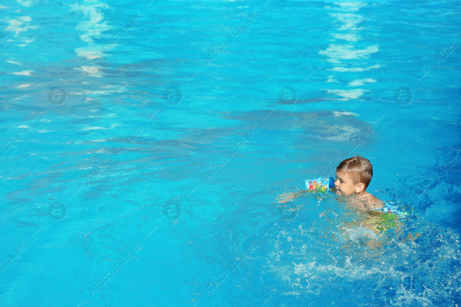 Photo of Little boy in swimming pool on sunny day