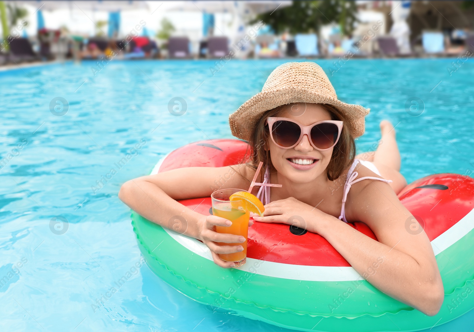 Photo of Young woman with cocktail in pool on sunny day