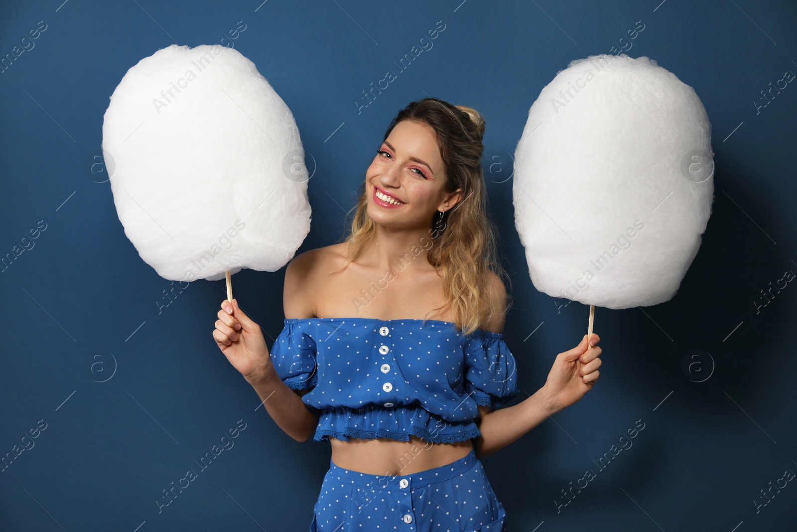 Photo of Portrait of pretty young woman with cotton candy on blue background