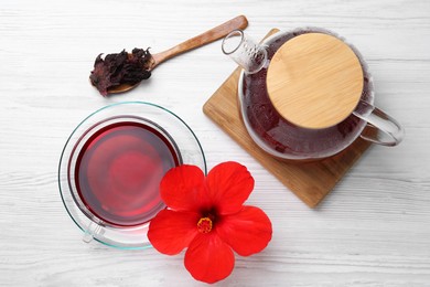 Delicious hibiscus tea and flowers on white wooden table, flat lay