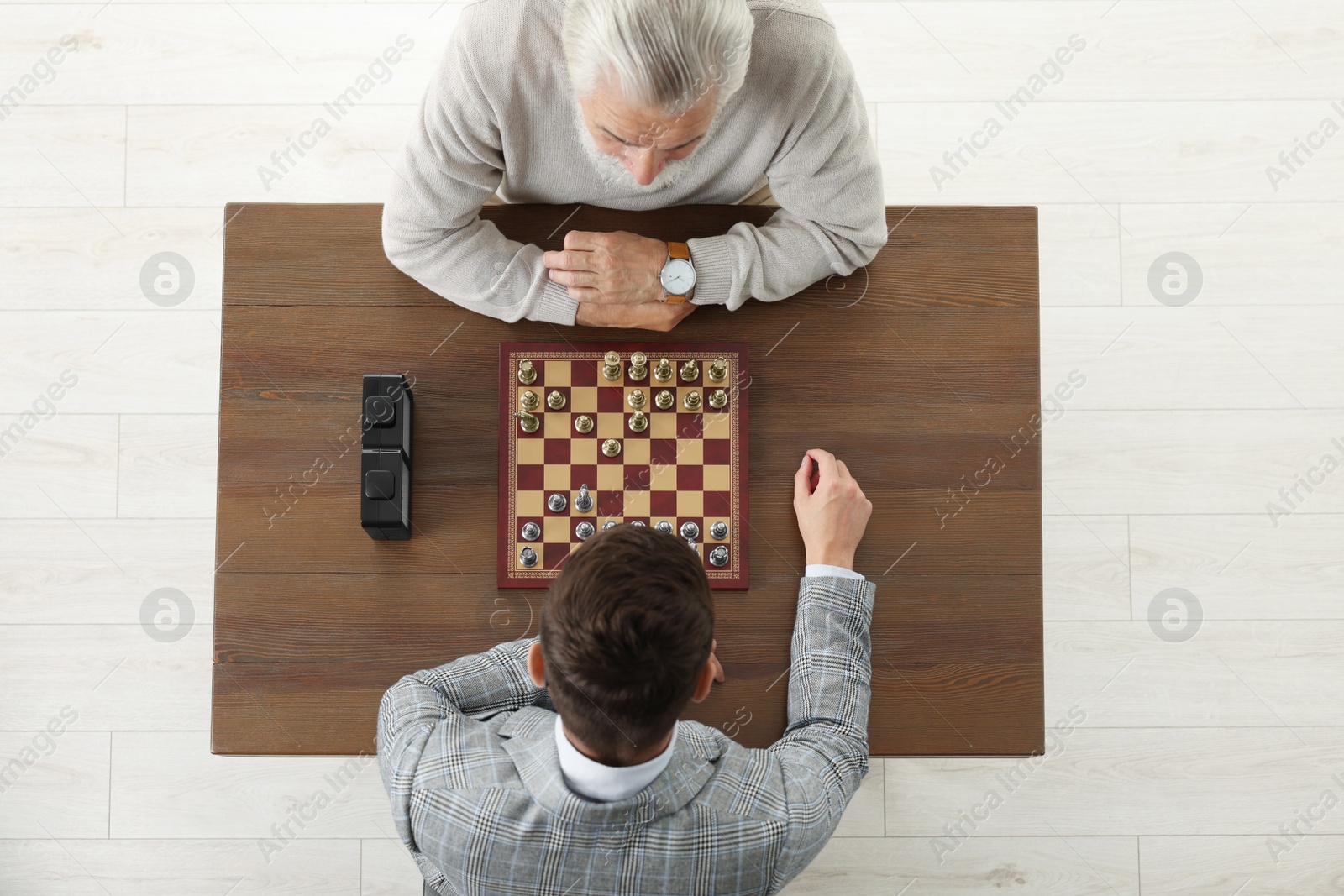 Photo of Men playing chess during tournament at wooden table, above view