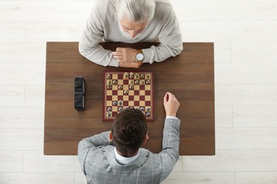 Men playing chess during tournament at wooden table, above view