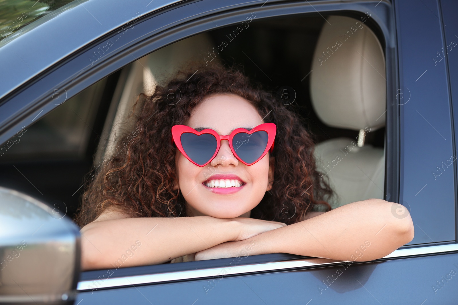 Photo of Young beautiful African-American woman wearing heart shaped glasses in car