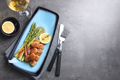 Photo of Delicious fried scallops with asparagus served on grey table, flat lay. Space for text