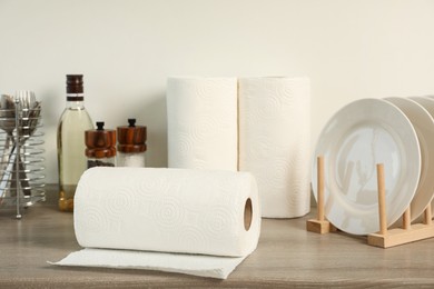 Photo of Many rolls of white paper towels and other kitchen stuff on wooden countertop near light wall